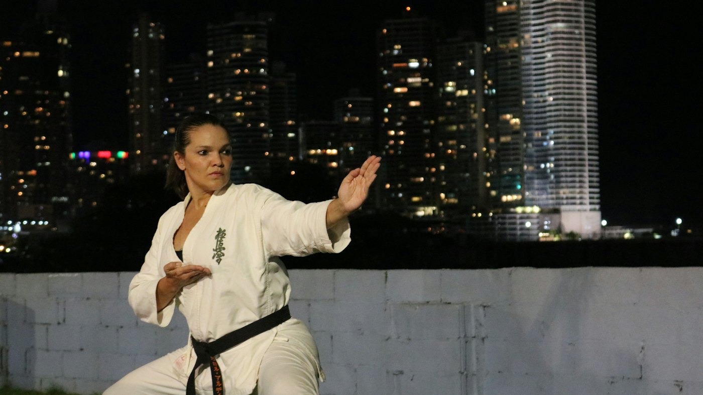 Mujer practicando kárate frente a las luces de la ciudad