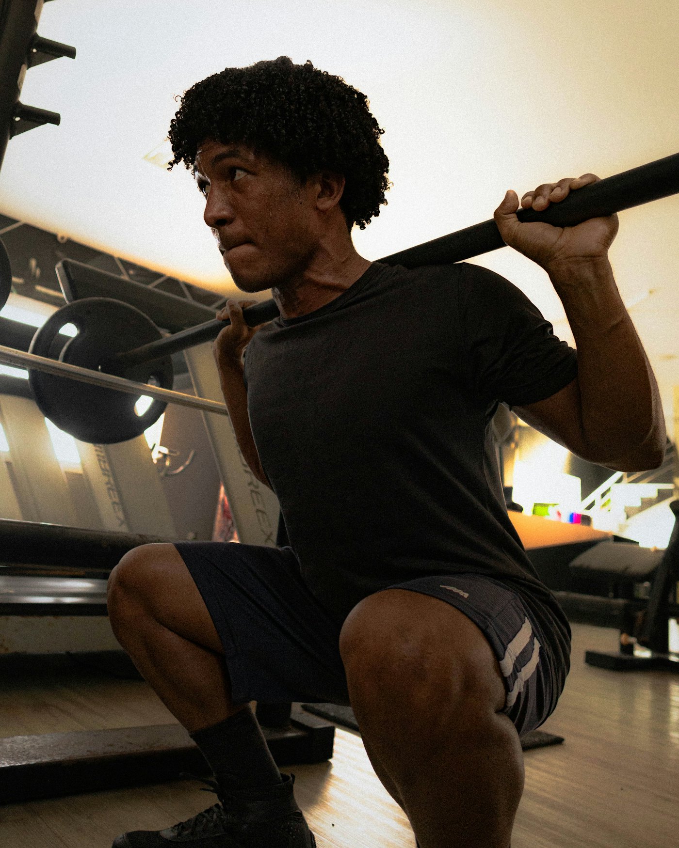 Hombre haciendo sentadilla con barra en un gimnasio